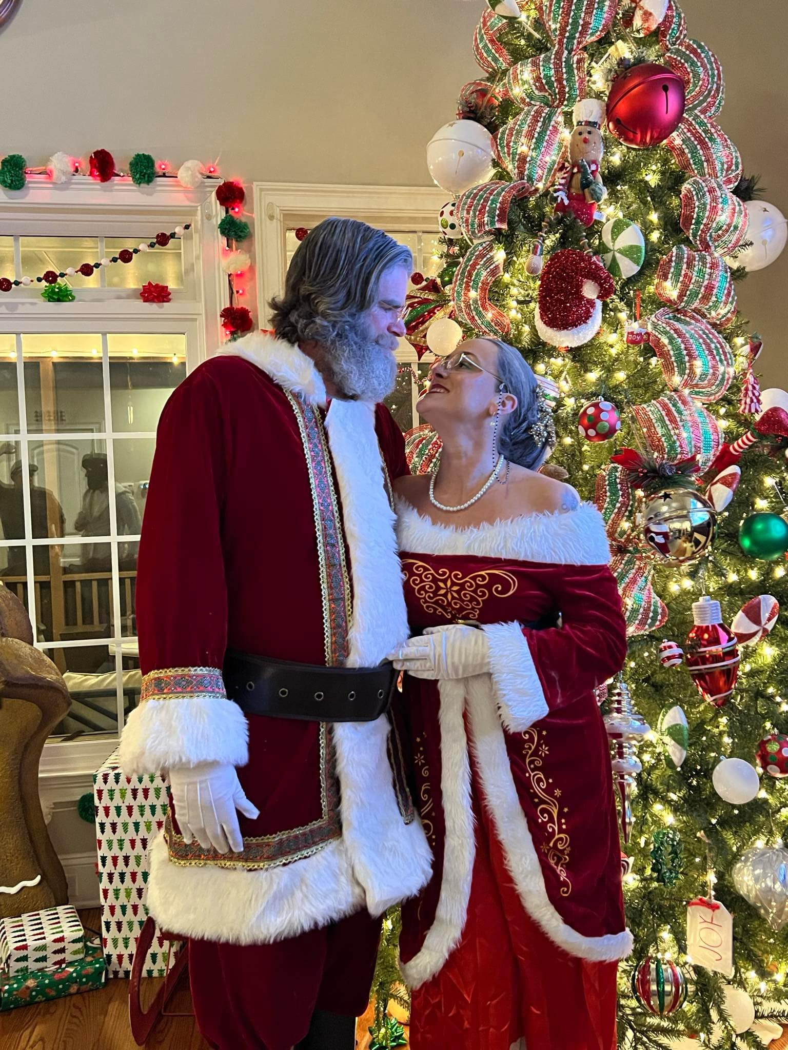 Santa and Mrs. Claus in front of a beautifully decorated Christmas tree